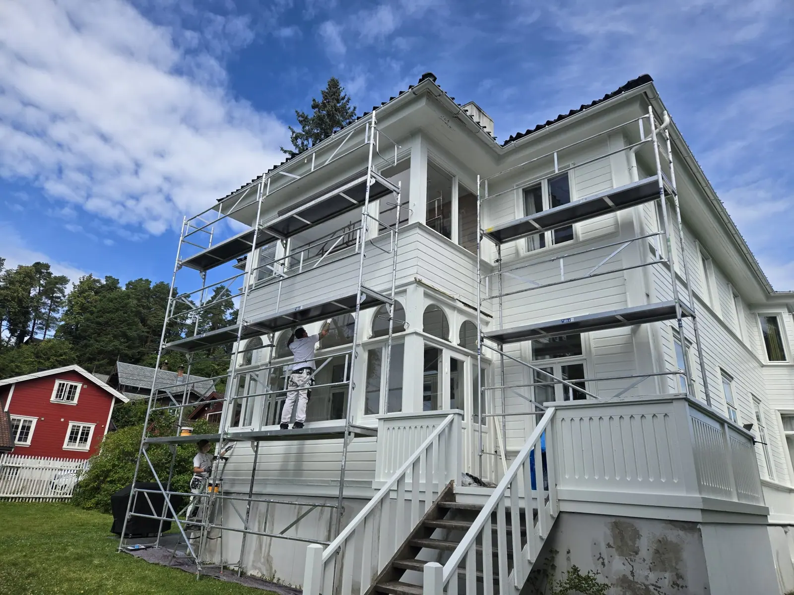 Maler på stillas ved hvit villa med veranda