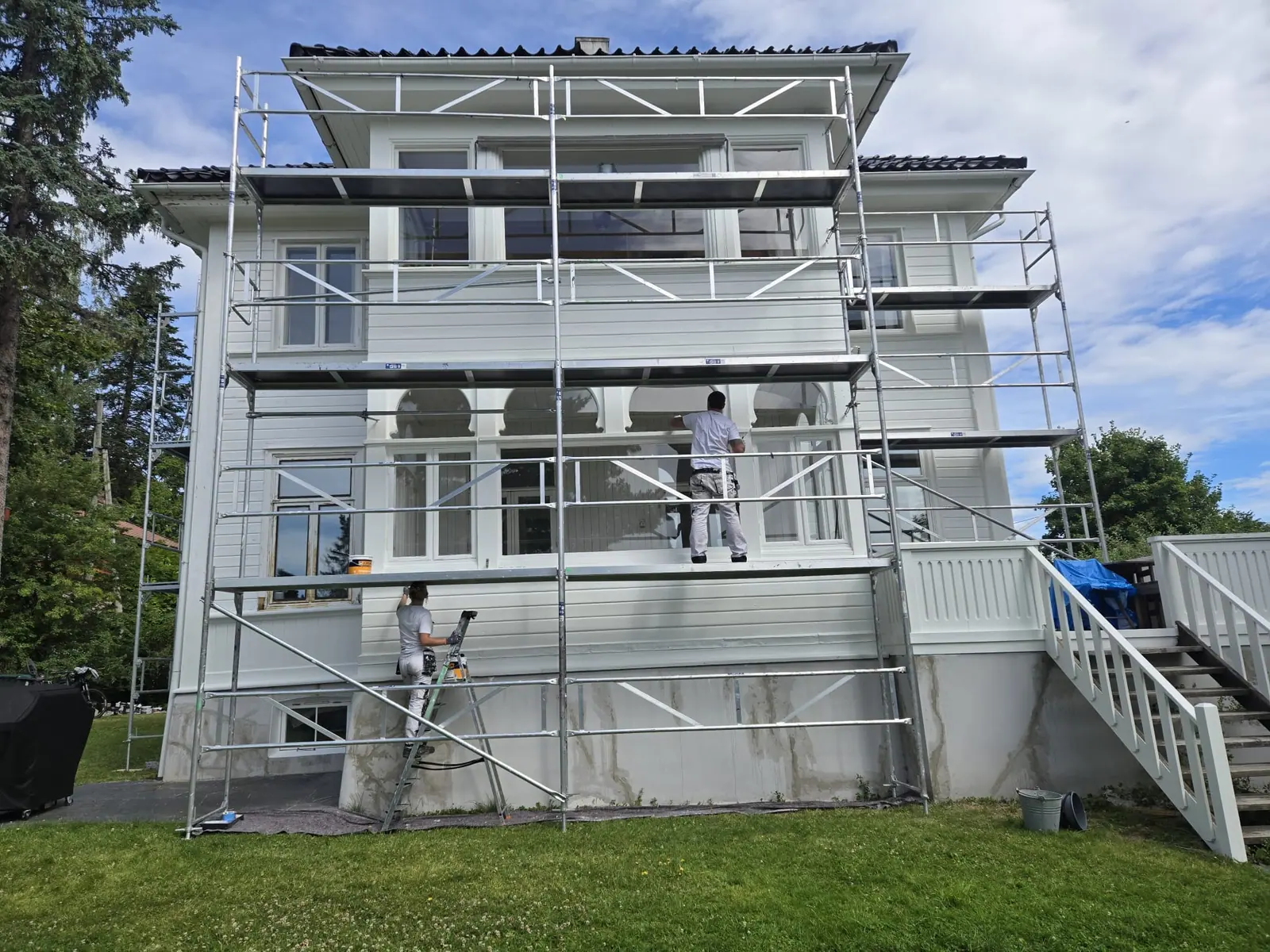 Malere i arbeid på stillas ved en hvit villa