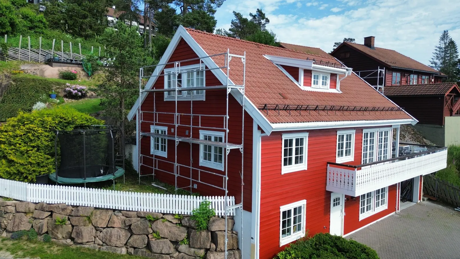 Rødt hus med hvite vinduer etter utvendig maling
