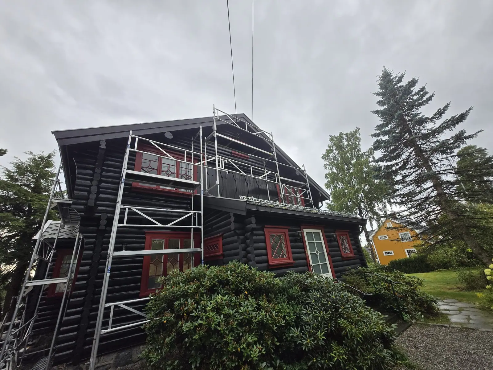 Tømmerhus med mørk beis og stillas