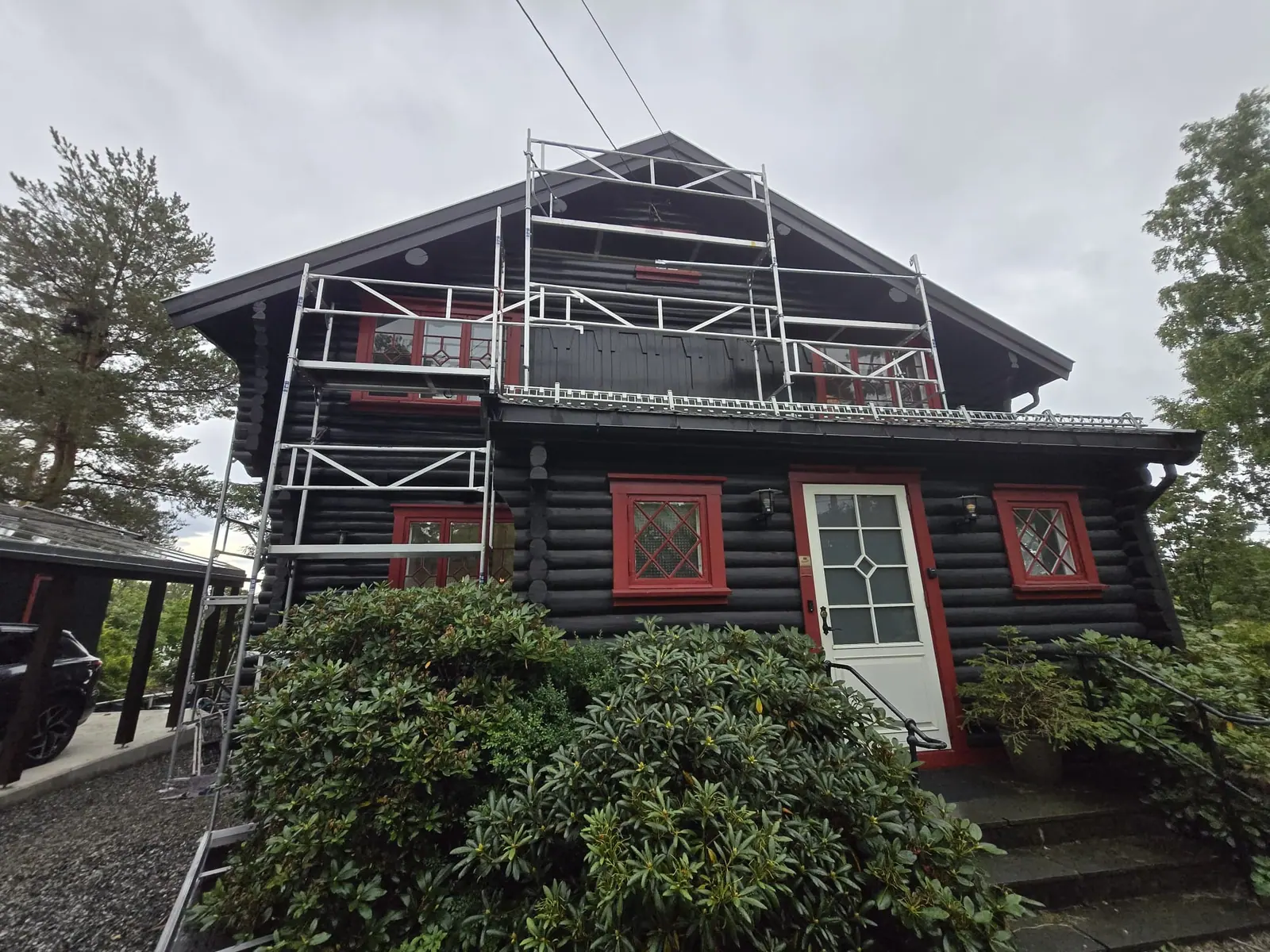 Tømmerhus med røde vinduer og stillas