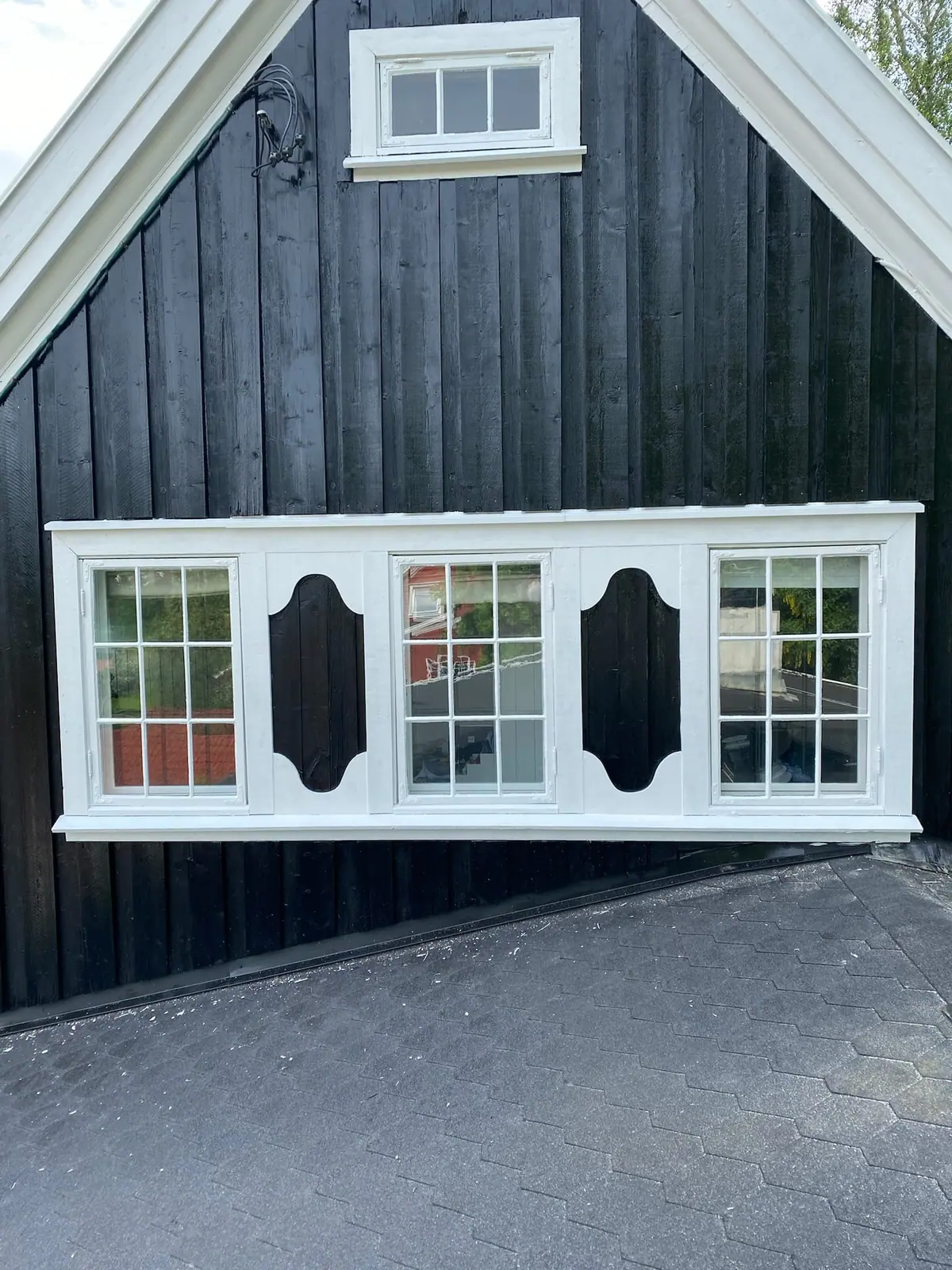 Nymalte vinduer med hvite rammer på mørk kledning